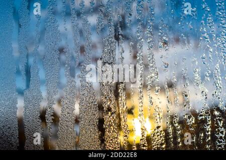 Gefrorenes Wasser tropft an einem Wintermorgen auf das Fensterglas. Stockfoto