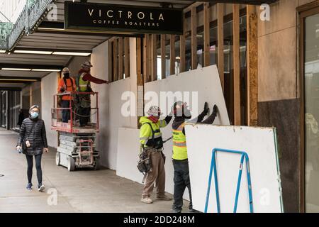 Seattle, USA. November 2020. Mittagspersonal, die Bretter abholten, die die Fenster im Victrola Coffee im Amazon-Gebäude bedeckten. Stockfoto