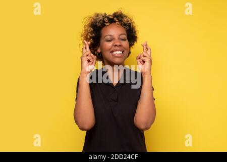 afroamerikanisches Mädchen, das die Finger kreuzt für Glück und Lächeln Freudig beten für Traum wahr werden oder Wunsch zu machen Stockfoto