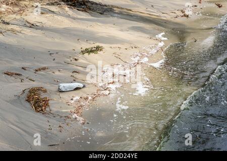 Sand Meer oder See Strand verschmutzt mit Plastikflaschen und schwarzen schädlichen giftigen Abwasserchemikalien. Natur kontaminiert mit Industriefabrik oder Anlage Stockfoto