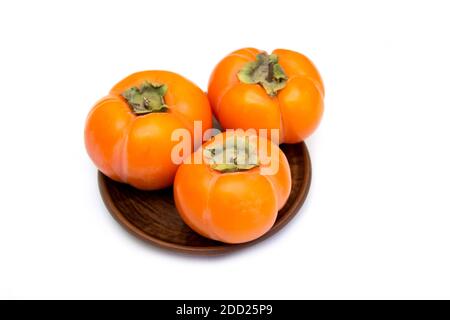 Persimmon. Vitamine im Winter, drei reife Kaki auf einem Teller Stockfoto