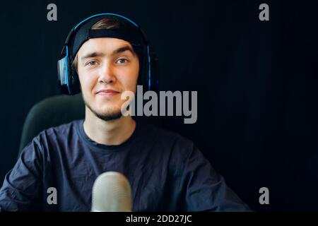 Cyber-Sport. Handsome Spiel Streamer gewinnt eine Runde in einem wettbewerbsorientierten Spiel. Streaming von Online-Spielen im Internet. Der Typ mit den Kopfhörern zeichnet die Stimme auf. Stockfoto