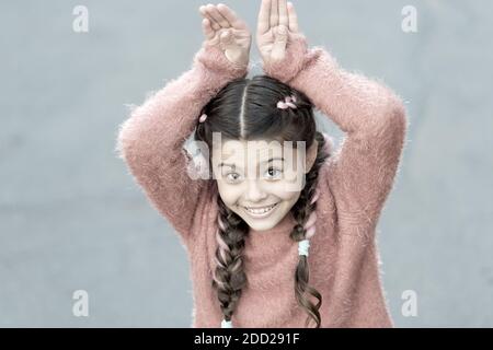 Cute Bunny. Frohe Ostern. Urlaub Bunny Girl posiert wie Kaninchen grauen Hintergrund. Kind lächelnd spielen Bunny Rolle. Verspieltes Baby feiern Ostern. Frühlingsferien. Talent und Handeln. Glückliche Kindheit. Stockfoto