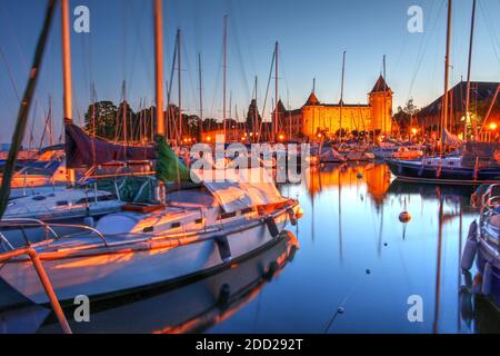 Sonnenuntergangsszene am Genfersee in Morges, Schweiz mit dem Yachthafen und dem mittelalterlichen Chateau de Morges. Stockfoto