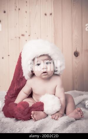 Baby in Weihnachten mit einem großen Weihnachtsmann Hut Stockfoto