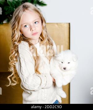 Kind mit Hund Welpe Samoyed auf einem hellen Hintergrund. Haustier und Kinder Konzept. Haustier im Kindesalter. Stockfoto