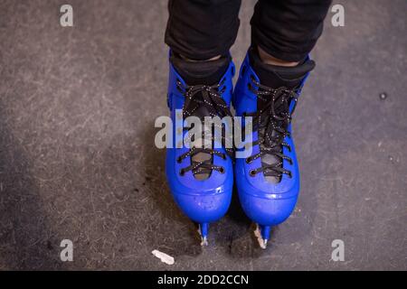 Leuchtend blaue Schlittschuhe auf einer speziellen Eislauffläche. Wassertropfen und Eisstücke. Sportschuhe für Hockey oder Eiskunstlauf. Das Konzept des Wintersports Stockfoto