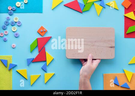 Kreatives Design für Autism Welttag mit Tangram Puzzle Dreiecke, Piktogramm und Hand mit Brett Stockfoto