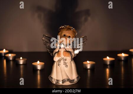 Weißer Weihnachtsengel mit brennenden Kerzen in der Kirche. Spirituelle Gottheit in der Religion. Stockfoto