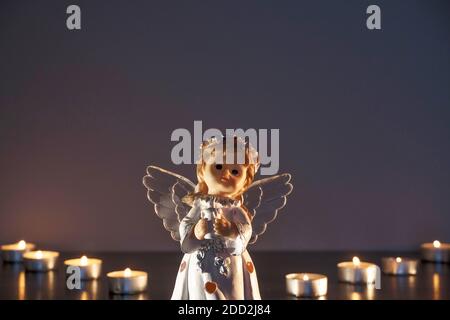 Weißer Weihnachtsengel mit brennenden Kerzen in der Kirche. Spirituelle Gottheit in der Religion. Stockfoto