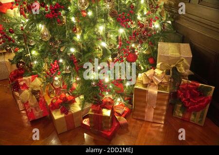 Wunderschön eingewickelt von Geschenken unter dem Weihnachtsbaum mit Lichtern Stockfoto