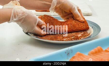 Geräucherter Paprika gerösteter Lachs Rezept. In Paprika, Pfeffer und Salz marinierte Fischstücke. Frau Hände, Kochvorgang Stockfoto