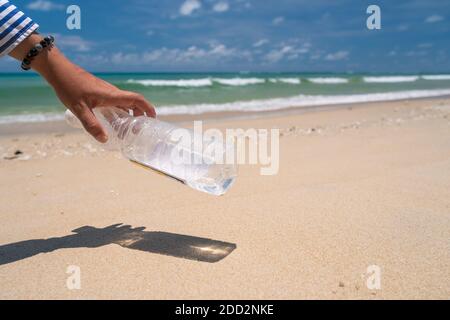 Holen Sie sich am wunderschönen Strand leere Wasserflaschen oder Müll mit der Hand. Umwelt Problem der globalen Erwärmung. Stockfoto