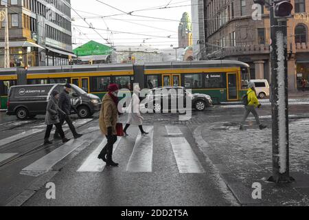 Helsinki, Finnland 20. November 2020 Menschen überqueren die Straße, erster Schnee auf den Straßen der Stadt. Hochwertige Fotos Stockfoto