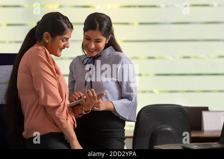 ZWEI WEIBLICHE FÜHRUNGSKRÄFTE ARBEITEN GERNE ZUSAMMEN AN EINEM DIGITALEN TABLET Stockfoto