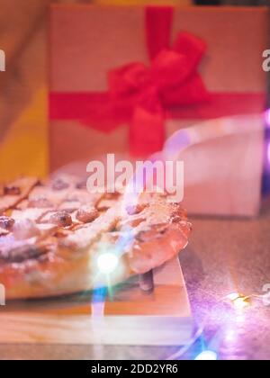 Apfelkuchen mit Rosinen und Zimt auf vintage Beton Hintergrund Textur. Mit Weihnachtsbeleuchtung, Draufsicht Stockfoto