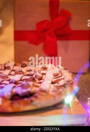 Apfelkuchen mit Rosinen und Zimt auf vintage Beton Hintergrund Textur. Mit Weihnachtsbeleuchtung, Draufsicht Stockfoto