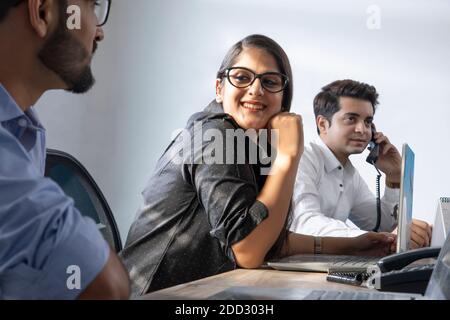 EINE JUNGE FRAU, DIE SICH WÄHREND DER ARBEIT MIT EINEM KOLLEGEN FREUT Stockfoto