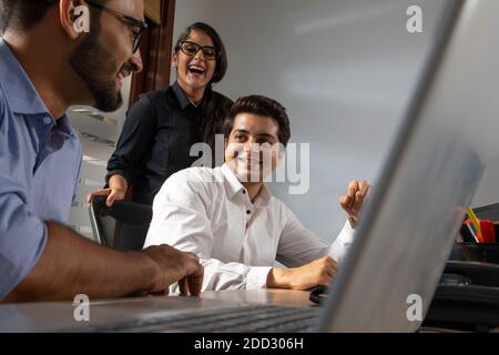 BÜROKOLLEGEN ARBEITEN GERNE IM BÜRO ZUSAMMEN Stockfoto