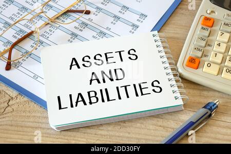 Asset and Liability wird auf einem Notizblock auf einem Schreibtisch mit Bürozubehör geschrieben. Stockfoto