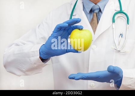 Ein Arzt in Schutzhandschuhen zeigt einen Apfel als Konzept für eine gesunde Ernährung und Lebensweise oder richtige Ernährung. Stockfoto