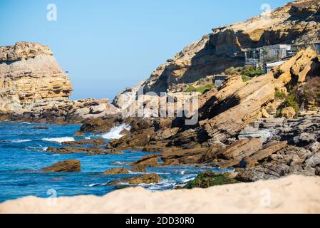 Steine und Felsen am Strand unter Himmel blauer Atlantik gegen die Klippen während sonniger Tag. Stockfoto