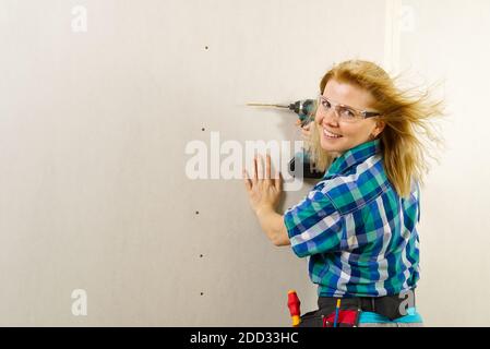 Blonde Frau mit Schraubendreher-Werkzeug in den Händen arbeiten zu Hause Verbesserung. Handywoman Konzept Stockfoto