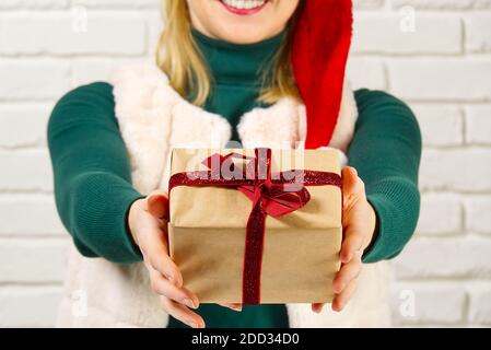 Weibliche Hände halten eine kleine Geschenkbox in Packpapier verpackt. Geschenke von Angehörigen zu weihnachten, Valentinstag, Geburtstag zu geben und zu empfangen. Stockfoto