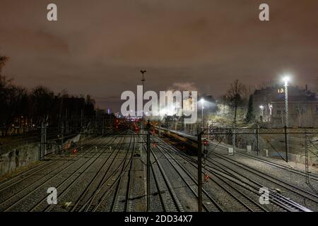 Nachtfoto einer alten Dampflokomotive, die entlang der Eisenbahnschienen läuft. Hochwertige Fotos Stockfoto