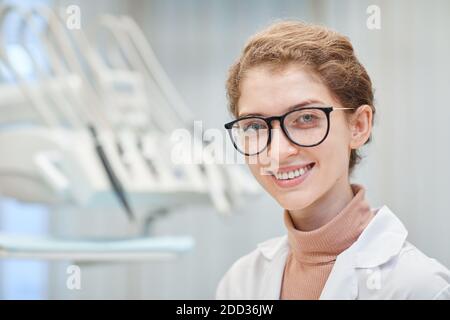 Nahaufnahme einer jungen Ärztin in Brillen, die die Kamera anlächelt Im Krankenhaus stehen Stockfoto