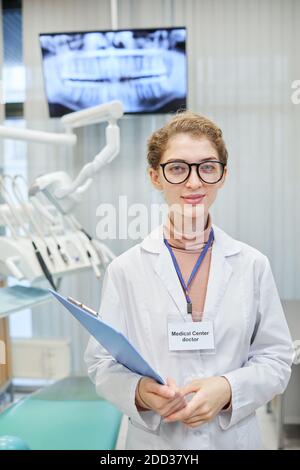 Porträt einer Ärztin in weißem Mantel mit ärztlicher Karte Blick auf die Kamera während der Arbeit in der Zahnklinik Stockfoto
