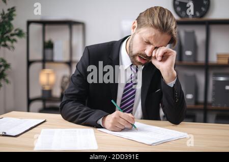 Müde Geschäftsmann Gähnen während Papierkram Stockfoto