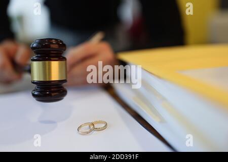 Richter hält hölzernen Gavel in der Nähe von zwei Eheringe close-up Stockfoto