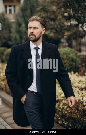 Bärtiger Mann im Anzug, der im Freien läuft Stockfoto