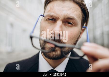 Reifer Geschäftsmann, der auf der Straße Brillen anlegt Stockfoto