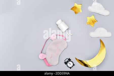 Gesundes Schlafkonzept. Medizinische Kapseln und Wecker auf grauem Hintergrund. Melatonin- und zyrkadiane Rhythmen. Unbranded Flasche mit Schlaftabletten. mond und Sterne Hintergrund. Schlafmaske. Stockfoto