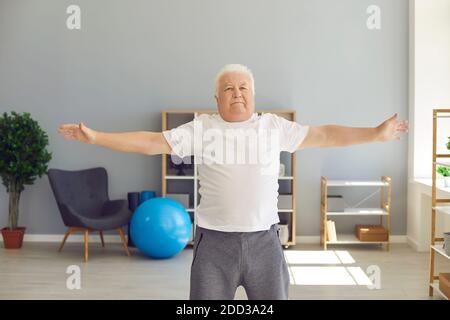 Reife grauhaarige Mann macht Übungen oder leichte Fitness-Training Zu Hause oder Rehabilitationsklinik Stockfoto