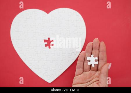 Womans Hand hält letzte Stück von Puzzles in Form von Nahaufnahme des Herzens Stockfoto