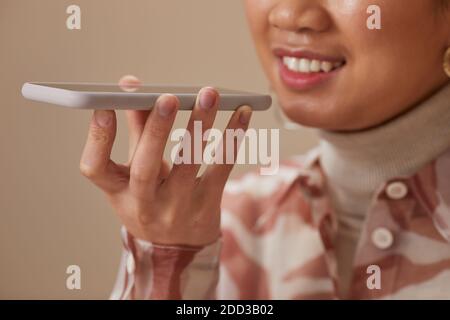 Nahaufnahme einer lächelnden Frau, während sie eine Audionachricht aufzeichnet Mobiltelefon Stockfoto