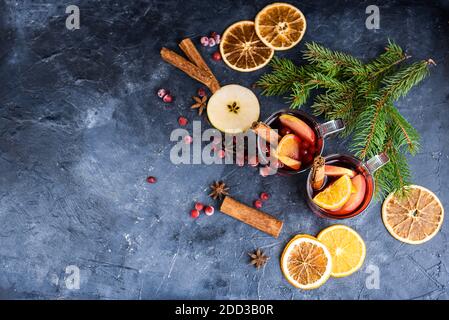 Zwei Tassen weihnachtlicher Glühwein oder Gluhwein mit Gewürzen und Orangenscheiben auf rustikaler Tischansicht. Traditionelles Getränk im Winterurlaub. Neue Jahre c Stockfoto