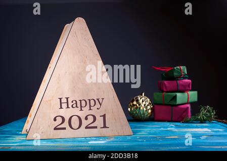 Holzboxen mit einem Überraschungsgeschenk für die Feiertage, mit Zahlen von glücklichen 2021. Neujahrsinhalte, Spielzeug, Geschenke, Zweige im Hintergrund. Stockfoto