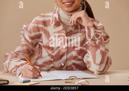 Nahaufnahme einer jungen Frau, die im Notebook schreibt und an der studiert Tabelle Stockfoto