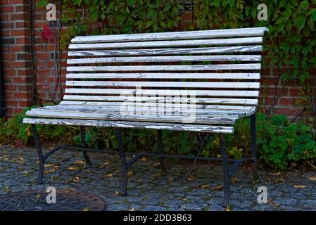 Abgenutzte alte weiße Parkbank aus Stahl und Holz mit abblätternder Farbe. Stockfoto