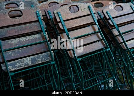 Klappstühle aus Stahl und Holz, die in mehreren Reihen zusammengebrochen sind. Stockfoto