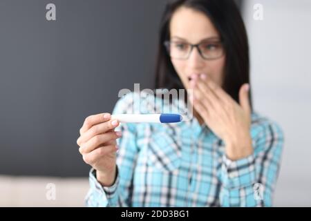 Überrascht junge Frau bedeckt ihren Mund mit der Hand und suchen Zu Hause beim Test Stockfoto