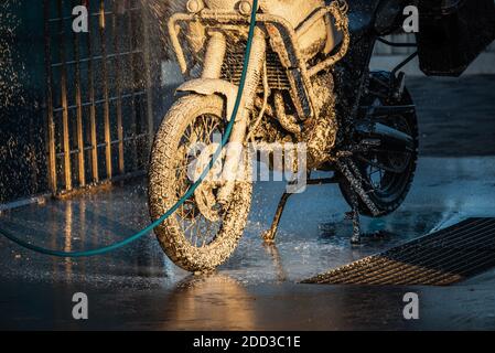 Waschserie für Motorräder. Ein Motorrad bei einer Autowäsche bei Sonnenuntergang waschen Stockfoto