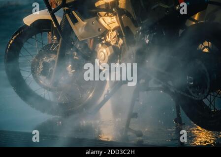 Waschserie für Motorräder. Ein Motorrad bei einer Autowäsche bei Sonnenuntergang waschen Stockfoto