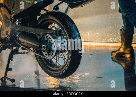 Waschserie für Motorräder. Ein Motorrad bei einer Autowäsche bei Sonnenuntergang waschen Stockfoto