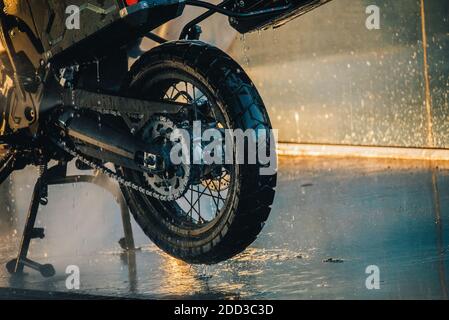 Waschserie für Motorräder. Ein Motorrad bei einer Autowäsche bei Sonnenuntergang waschen Stockfoto