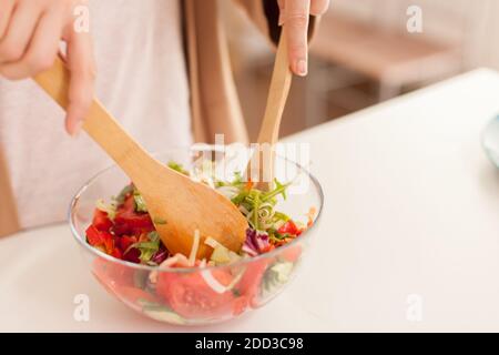 Nahaufnahme der Hausfrau Hände mischen Salat Zutaten in der Küche. Stockfoto